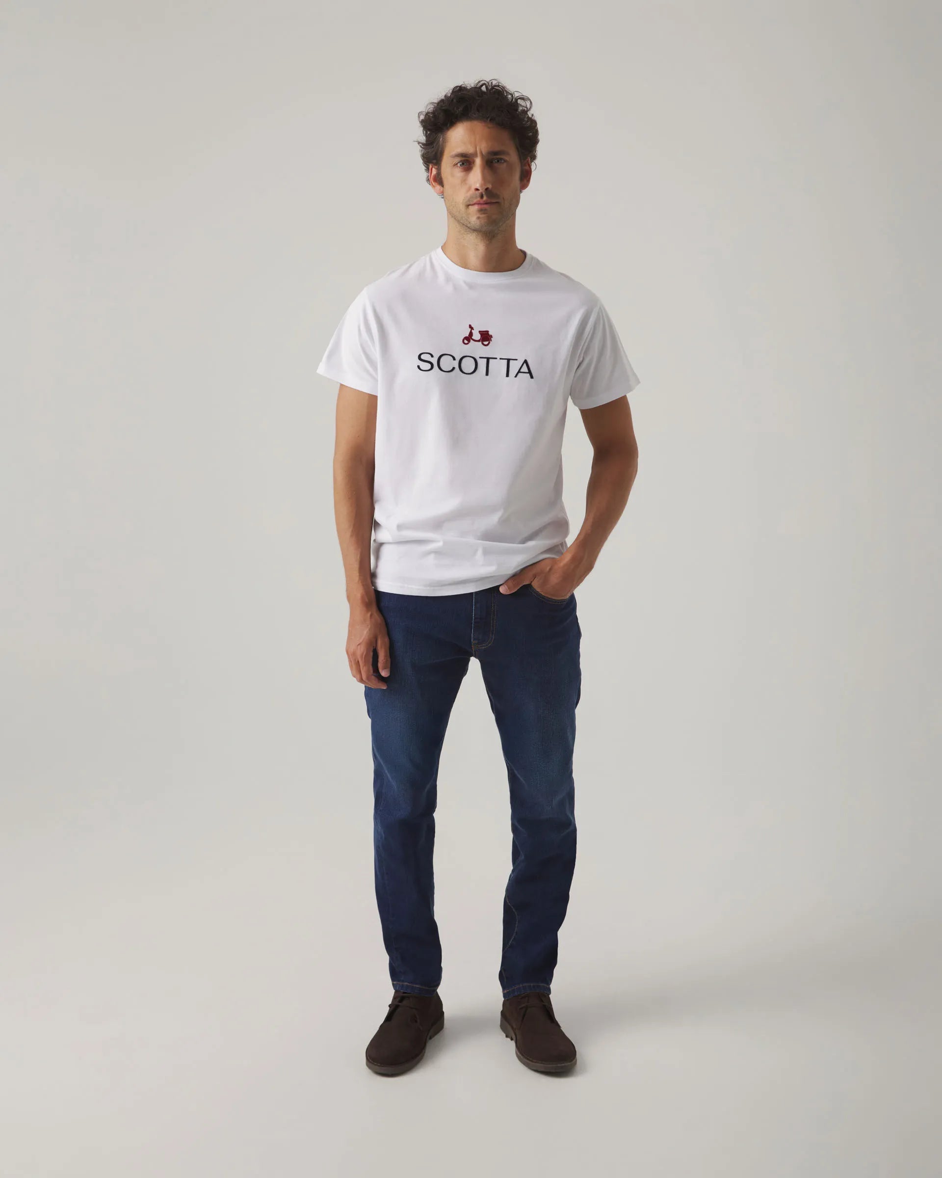 Camiseta blanca con cuello redondo y manga corta, con letras y moto Scotta en el torso.